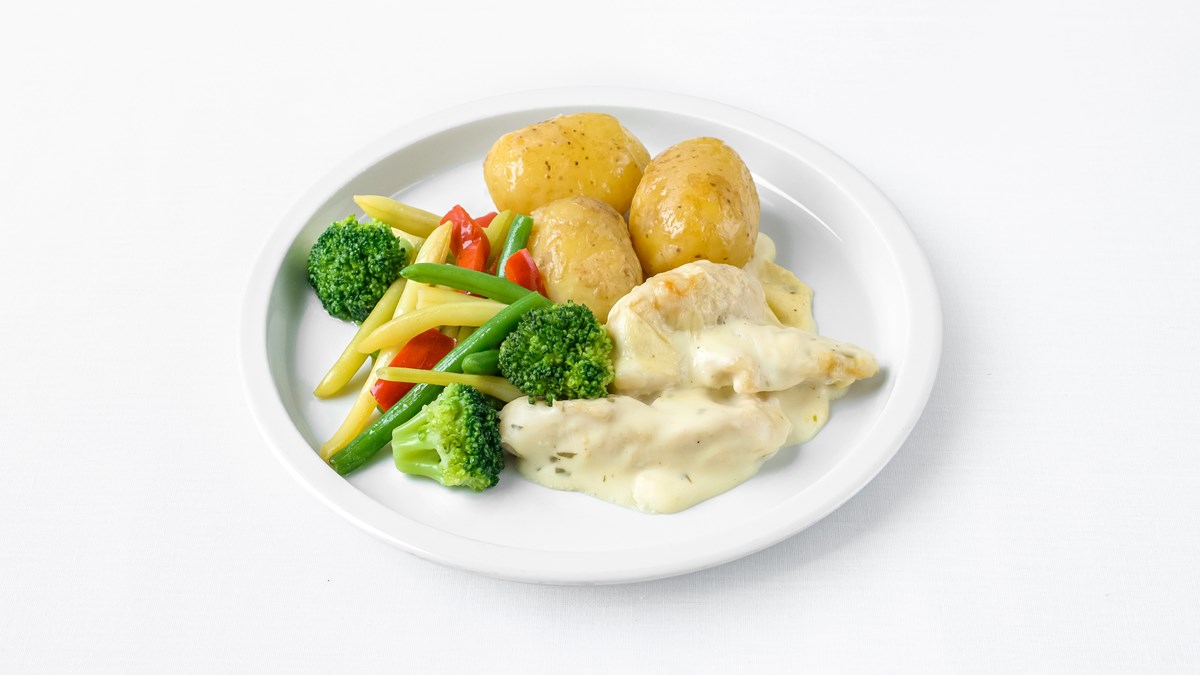 Bilden visar en tallrik med potatis, kyckling i sås och grönsaker. 